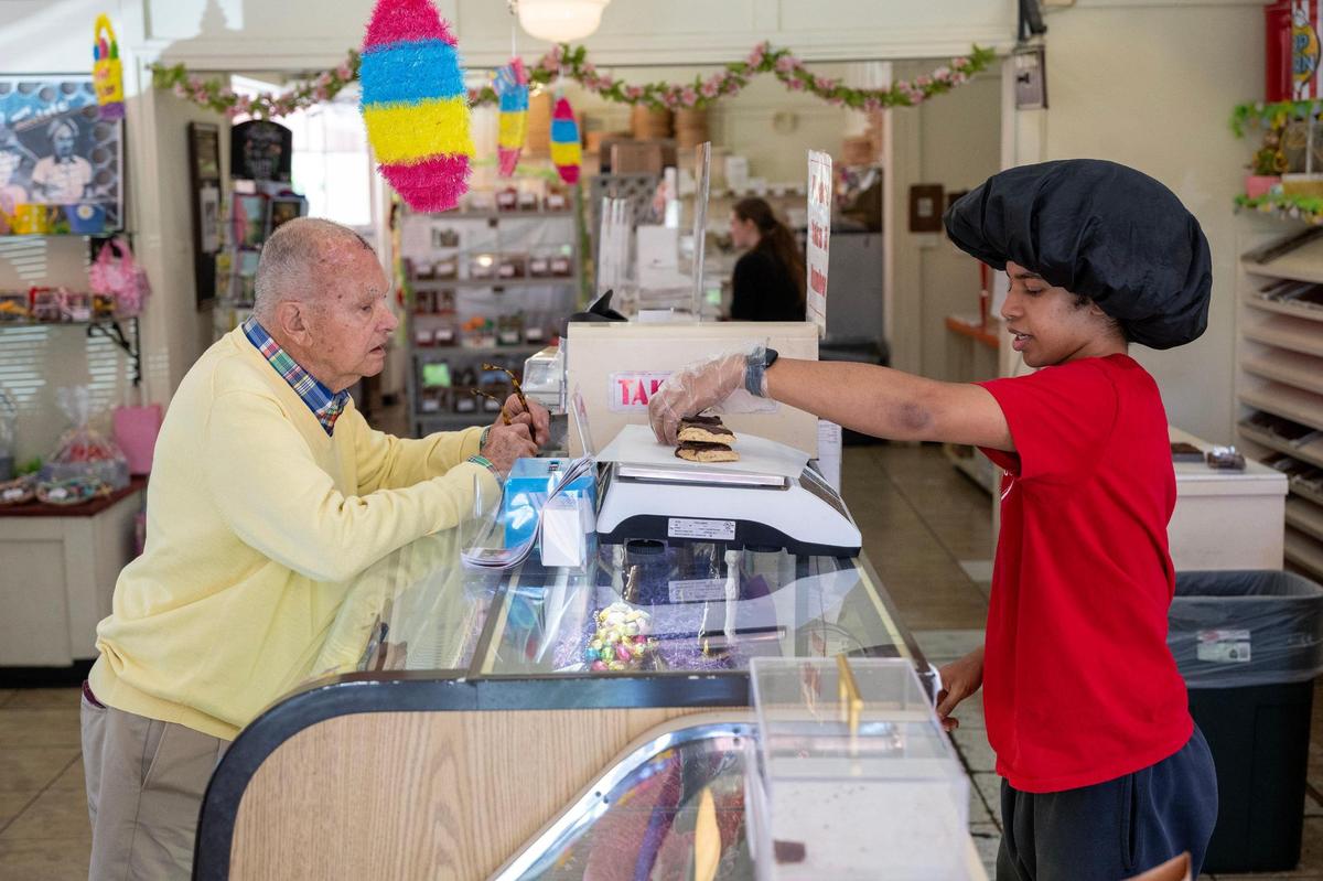 Russel Smith, right, helps a customer with a selection of handmade cookies on at Laura Little’s Candies in Prairie Village.
