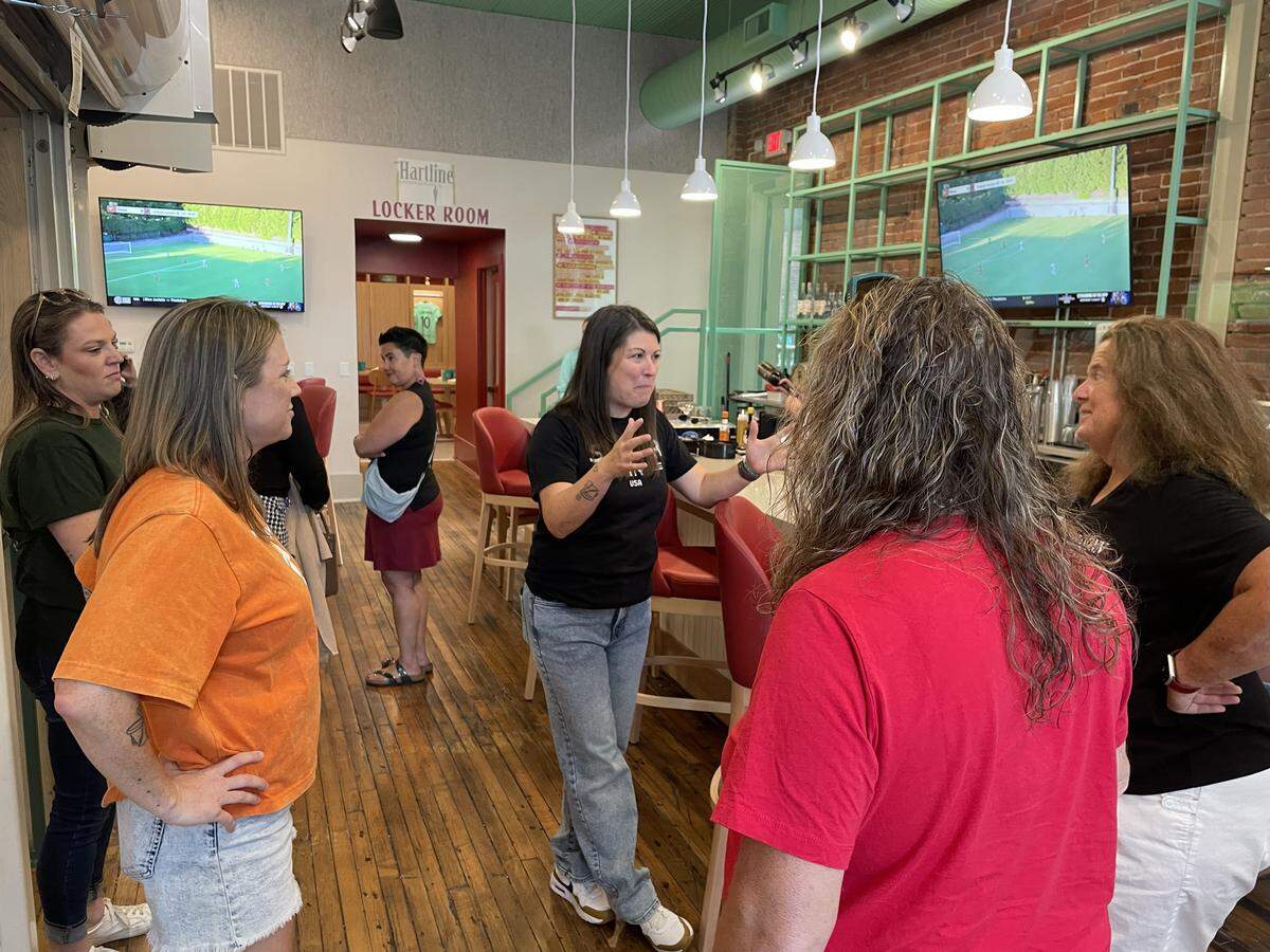 Monica Brady, center, speaks to guests who attended the soft opening of her sports bar, The Dub, on Thursday, Oct. 9. She and her partner, Rachel Glenn, left, have been working to open the space for a year and a half.