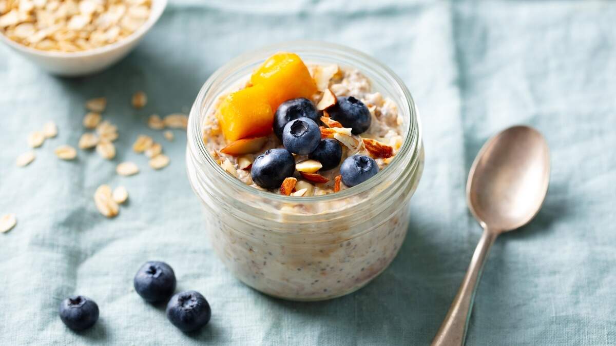 Healthy breakfast. Overnight oats with fresh berries and fruits in glass jars. Blue textile background. Close up. 30-30-30 Breakfast Ideas for a Protein-Packed Start to Keep You Full