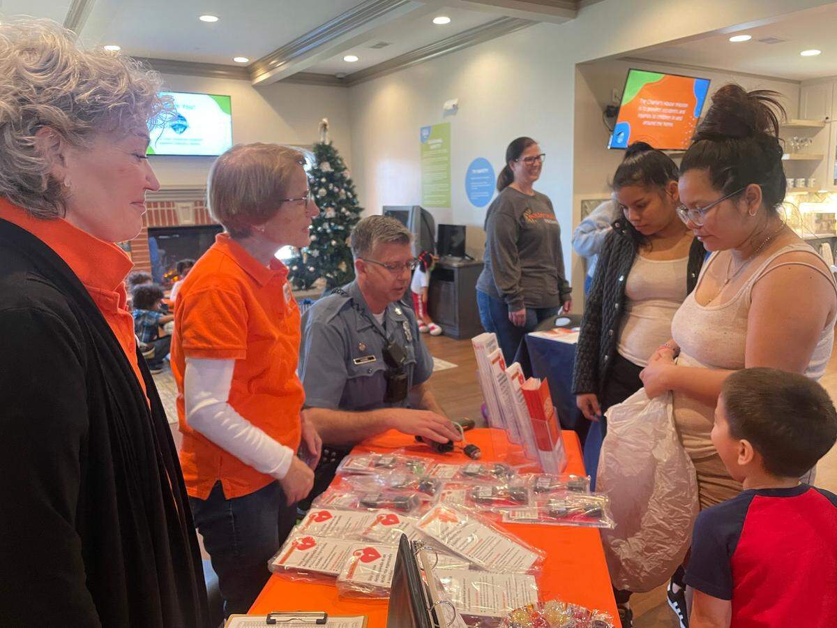 Grandparents for Gun Safety volunteers Gail Roberson and Ann Hall and Officer Andy Hamil, a KCPD community officer, hand out gun locks at Charlie’s House, a Kansas City organization focused on preventing kids from injury and death in the home, on Saturday, April 2. 