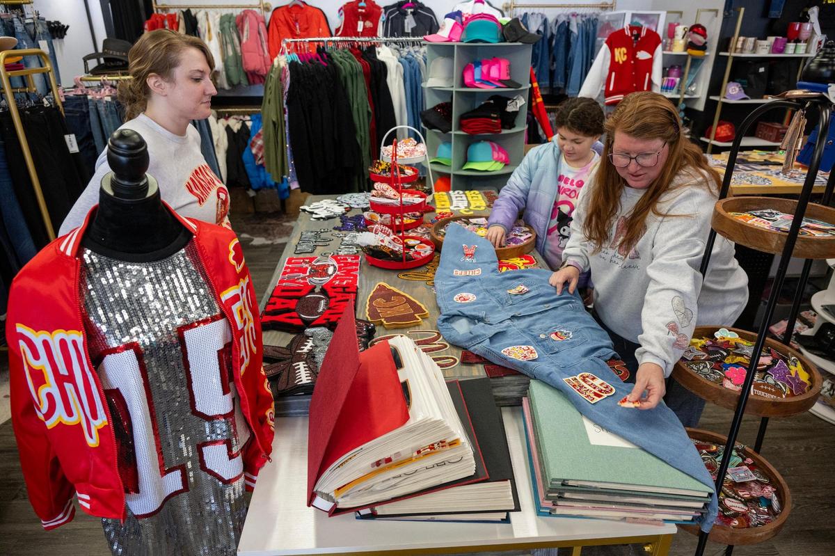 Stephanie Ault, left, a store employee, stands by to assist as as customer Amy Peña, right, of Blue Springs, adds Chiefs-themed patches to a jean jacket she was customizing at Maxi Laine’s Boutique on Saturday, Jan. 11, 2025, in Olathe. Peña’s daughter, Ava Peña, 9, was also on hand to help.