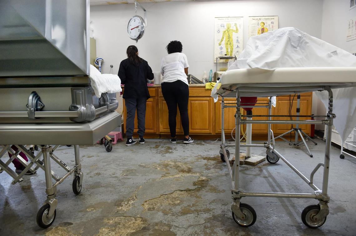 Amberlie Gonzalez, left, an assistant funeral director and apprentice embalmer, prepares a deceased man for viewing with Northern Star Mortuary owner and mortician Gwendelrae Hicks in Kansas City, Kansas. Hicks is concerned about the violence and has an idea to slow it.