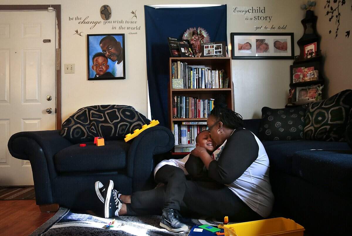 Jackson Portwood, 6, is kissed his grandmother Reba Rice-Portwood after playing at their apartment in the Jeff Vanderlou neighborhood on Wednesday, March 3, 2021. A painting of Reba’s son, Ricky Portwood, Jr., hangs on her wall alongside Jackson, who never met his father before he committed suicide at 22 on Sept. 17, 2014. Ricky’s fiancee found out she was pregnant with Jackson three days after his death. Photo by Robert Cohen, rcohen@post-dispatch.com