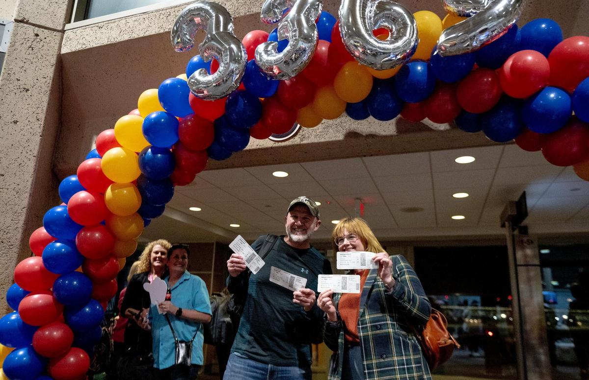 Eric Jaynes and Christy Keeling pose for a photo with their boarding passes before boarding the final flight to take off from Kansas City International Airport’s old terminals on Monday, Feb. 27, 2023, in Kansas City.