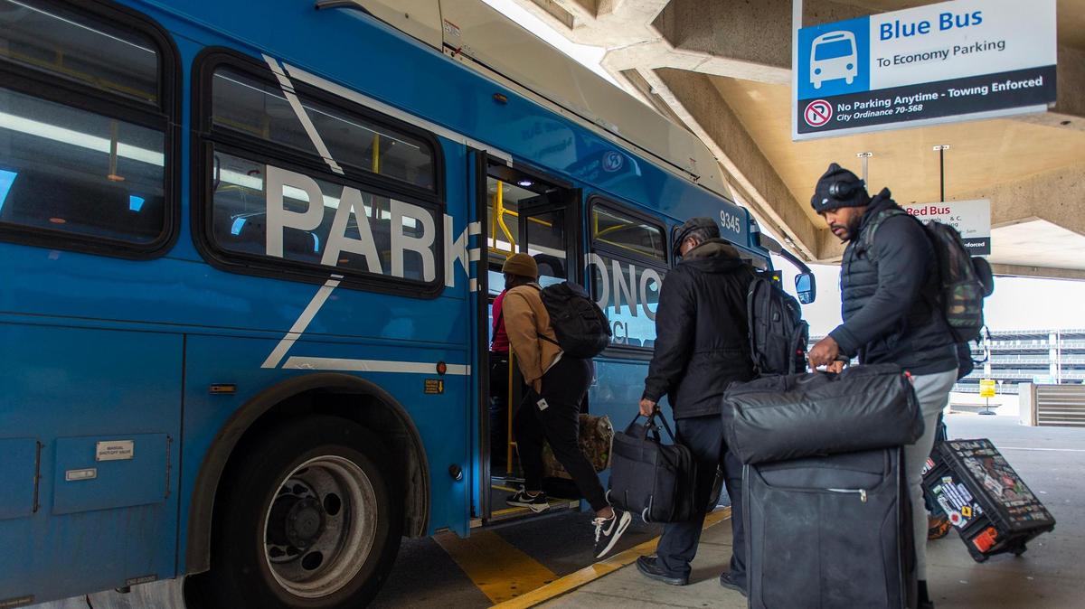 Travelers board the Blue Bus, an economy parking lot shuttle, outside of Kansas City International Airport’s Terminal B on Thursday, Dec. 1, 2022, in Kansas City.