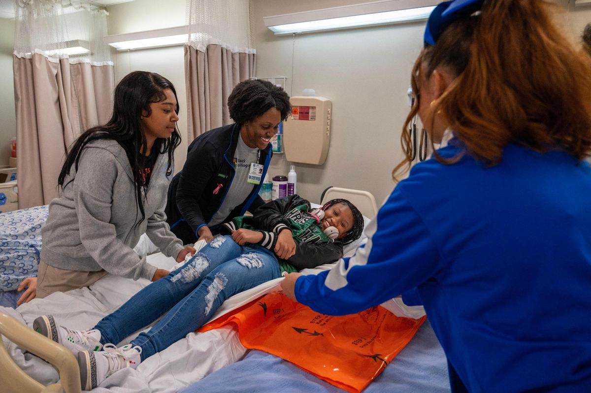 Shenita Fletcher, center, director of inpatient rehabilitation, demonstrates patient transfer between beds on Kenbry Hollinger, 15.