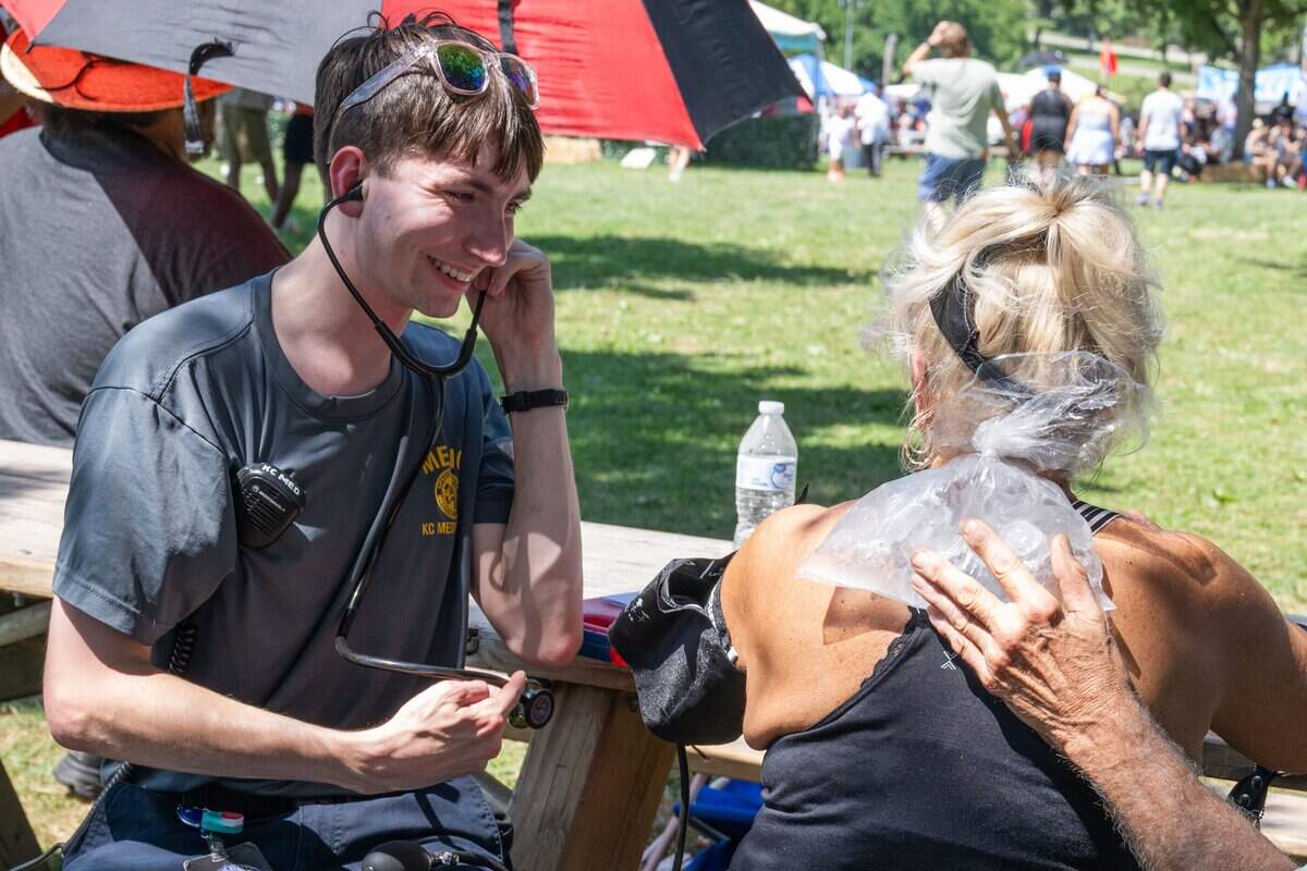 A paramedic assists a woman that was overheating at the Ethnic Enrichment Festival in Swope Park on Saturday, Aug. 16, 2025, in Kansas City. This year, festival goers braved nearly 100 degree heat.