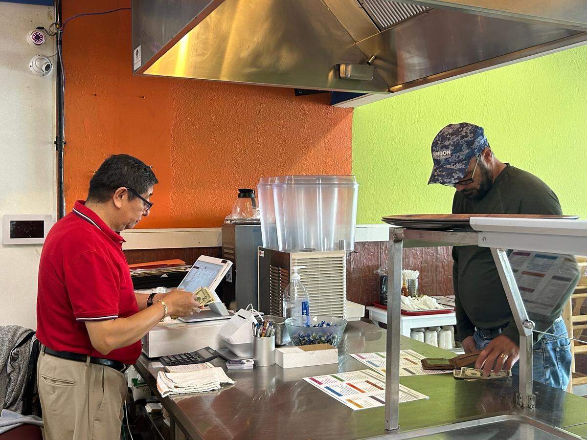 Martin Lopez rang up a customer at his new restaurant. The business fuses his Mexican culture with his wife’s Salvadoran one.