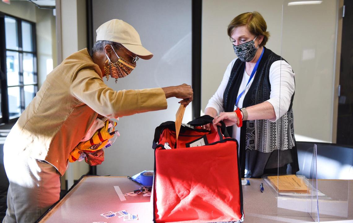 Joan Johnson, Mission, placed her primary election ballot in a ballot bag with the aid of supervising judge Susie Martin Tuesday while she voted at the Johnson County administration office building in Mission. The ballot tabulator was not working for a few minutes so ballots were placed in a bag.