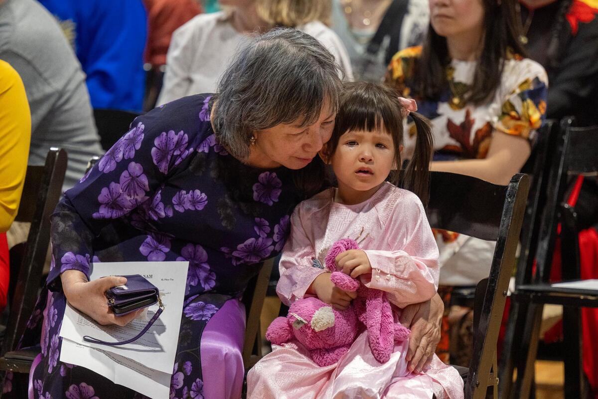 Tina Lê embraces her granddaughter, Mia Lê Shackelford, 3, during “Remembering Saigon.” Many of the people in attendance fled South Vietnam, including Lê.