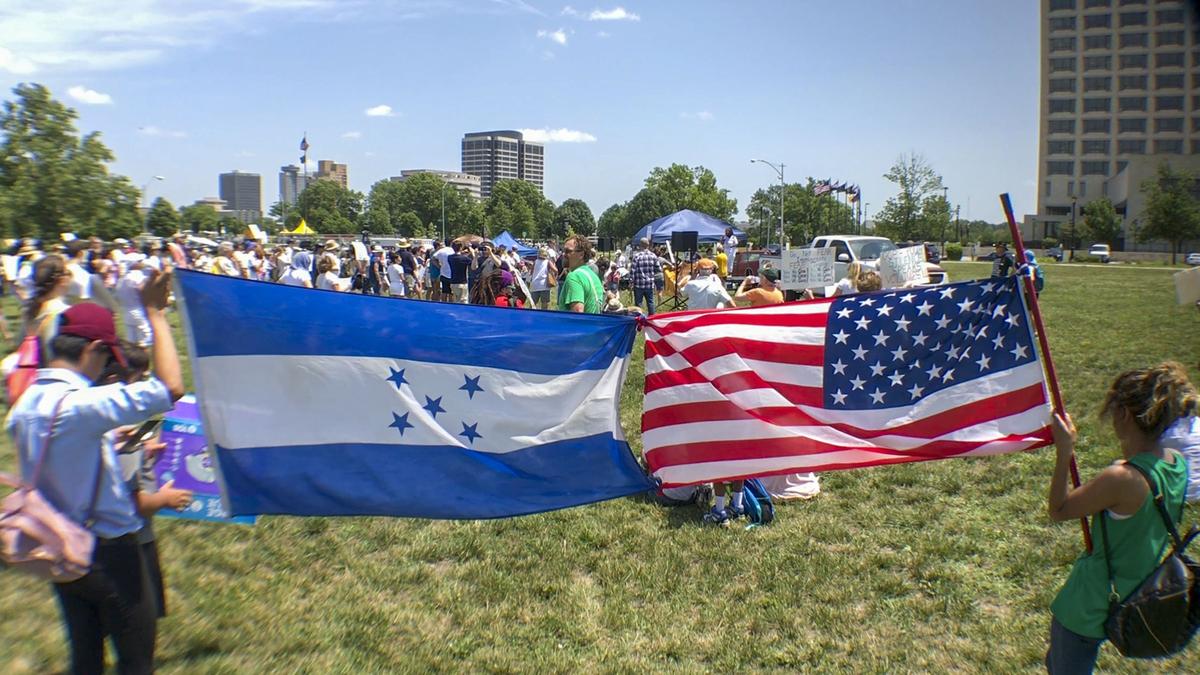 Laura Alcazar (right) and her brother hold up the American flag tied to the flag of Honduras during a rally protesting family separations at the border at Penn Valley Park on Saturday, June 30, in Kansas City, Kansas.