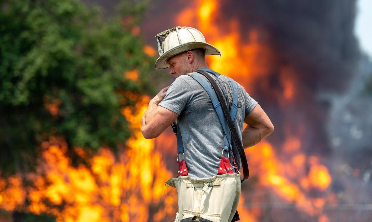 A firefighter uses his radio while fighting a blaze at Pioneer Pallet in the 3500 block of Nicholson Ave. on Thursday, June 15, 2023, in Kansas City.