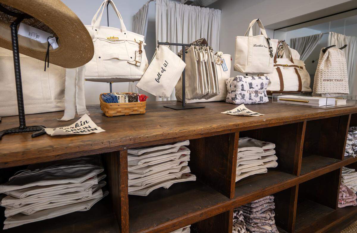 A collection of merchandise, including tote bags and hand towels, are displayed along a shelf at Larkin Home on Thursday, April 30, 2026, in Parkville.