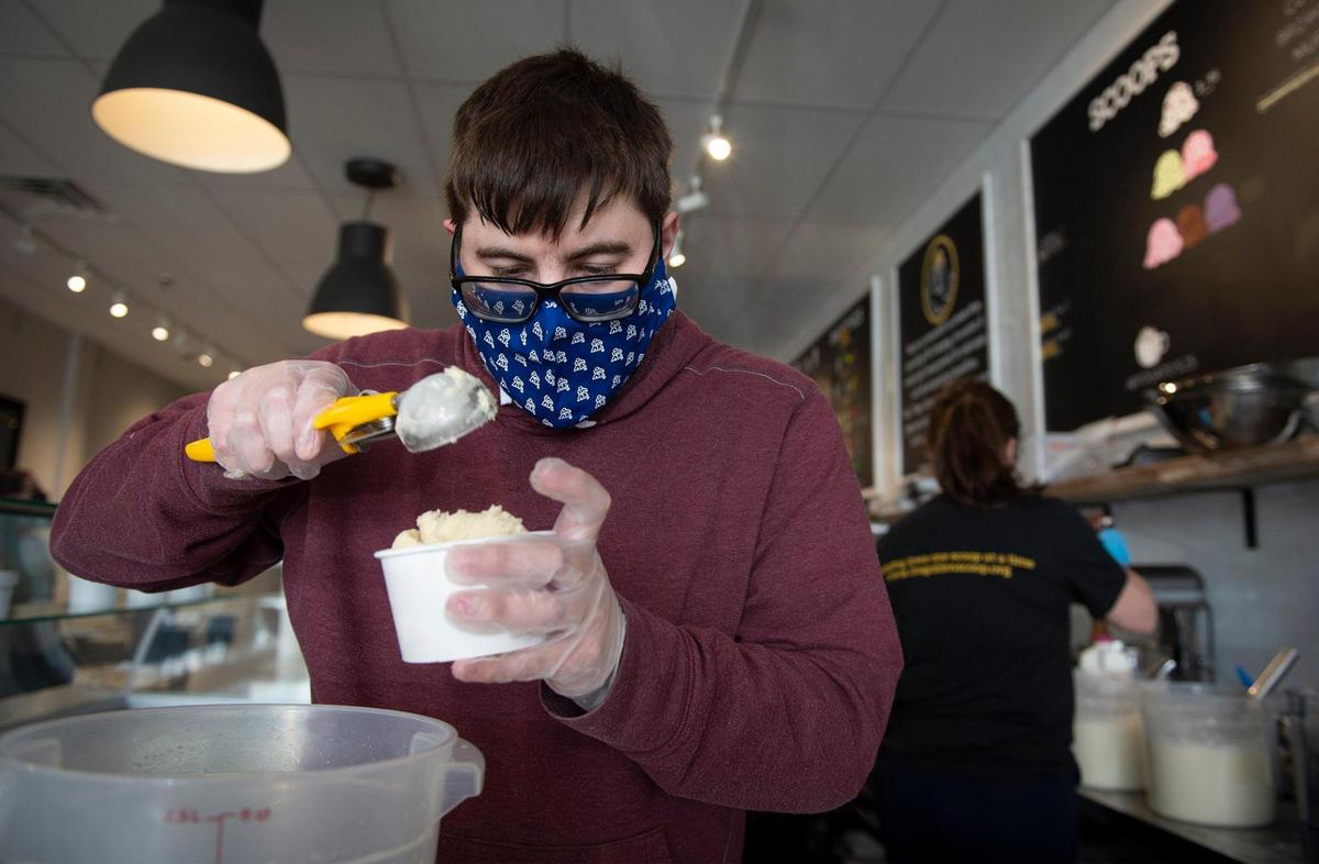 Ian Miller, 29, scoops ice cream into cartons Wednesday at The Golden Scoop, a new ice cream and coffee shop at 9540 Nall Ave., in Overland Park. The shop employs individuals with developmental disabilities. “Look around,” he said. “It’s got a great work environment and everybody is happy.”