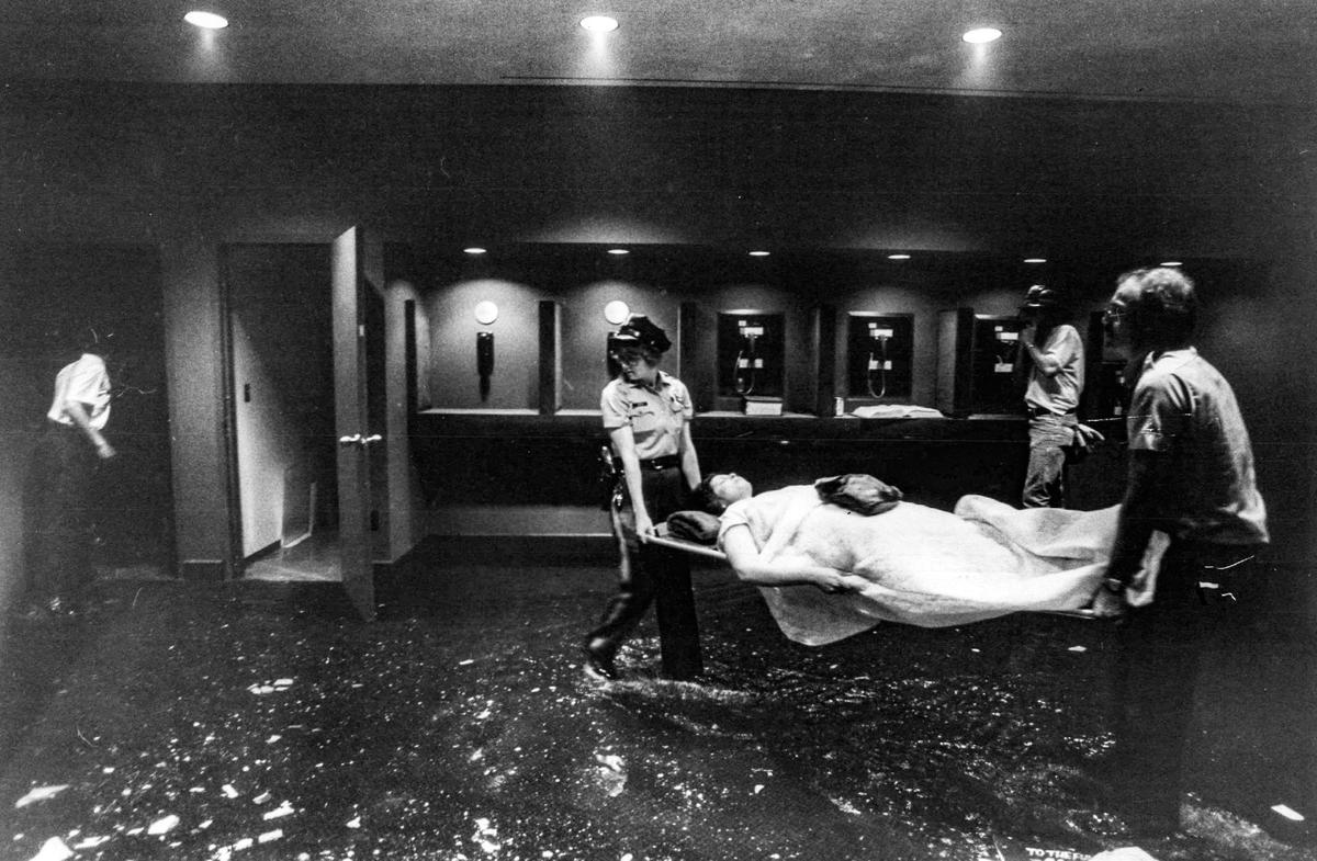 One of the hundreds of people injured in the collapse of the skywalks at the Hyatt Regency Hotel is carried to receive aid. Water from broken water lines due to the collapse covered the floor of the hotel.