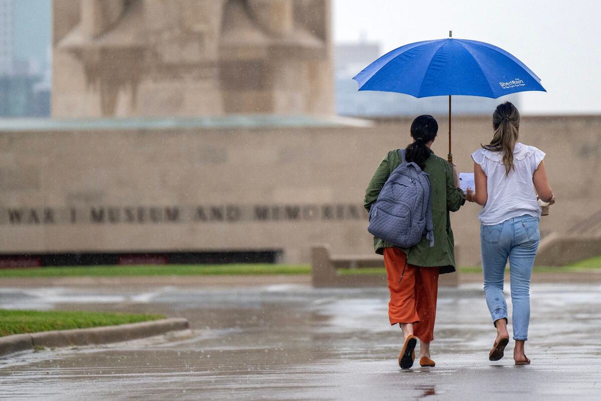 Holding an umbrella, visitors walk to the National WWI Museum and Memorial as rain begins to fall on Tuesday, July 16, 2024, in Kansas City.