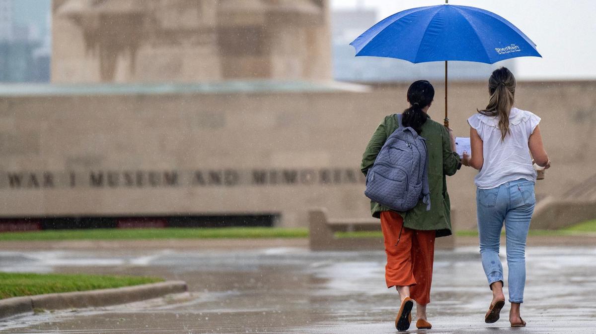Holding an umbrella, visitors walk to the National WWI Museum and Memorial as rain begins to fall on Tuesday, July 16, 2024, in Kansas City.
