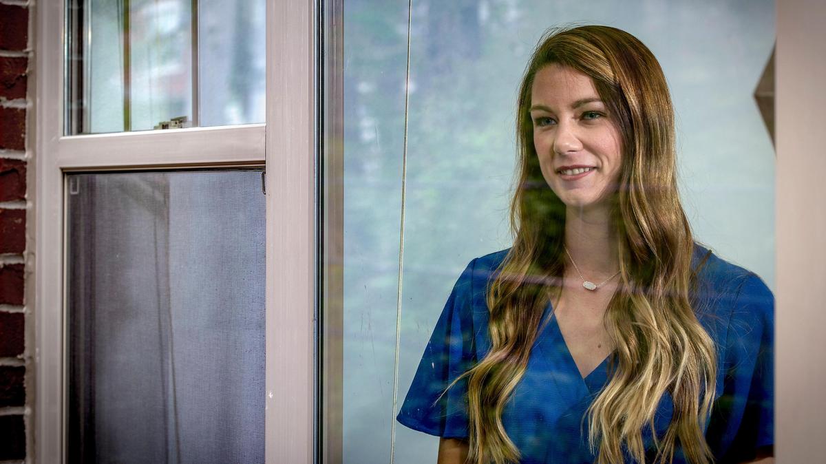 Registered nurse Julie French, 30, of Kansas City, peers out her window while quarantining in her apartment. French spent nearly a month working with COVID-19 patients in a hospital outside of Boston.