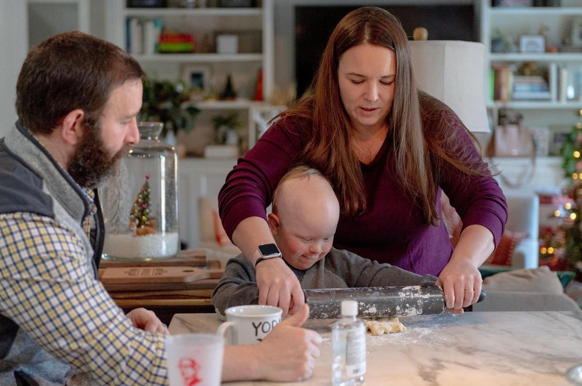 Sara Jahnke helps her son, Crosby Orlando, roll out cookies with his dad, Nick Orlando, in Prairie Village. The family is advocating for Kansas to fully fund special education, arguing that students like Crosby, who has Down syndrome, deserve more resources.