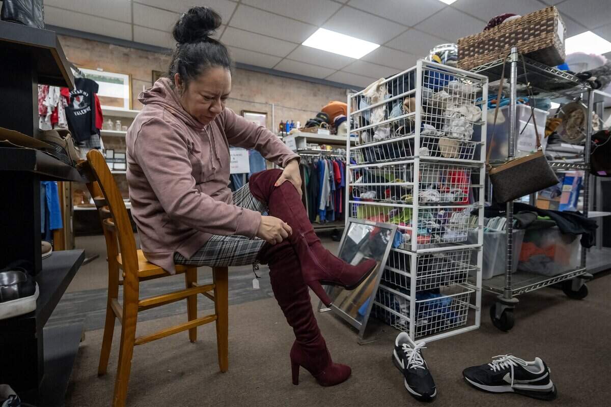 Betzaida Sanchez of Kansas City, Kansas, tries on a pair of thigh-high burgundy suede boots during a visit to Troost39 Thrift Store, 3922 Troost Ave., on Thursday, Jan. 15 2026, in Kansas City. Sanchez said she planned to purchase the like-new boots for $8.00.