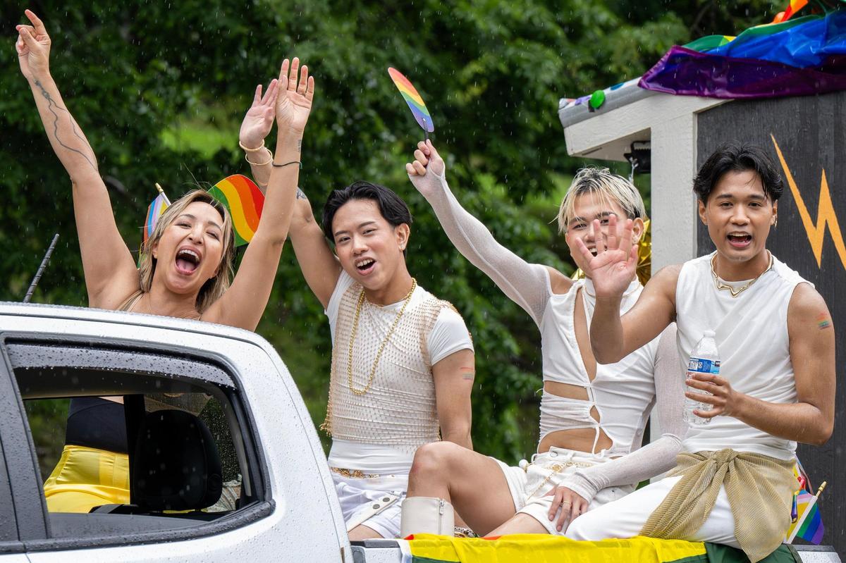Parade participants representing Cafe Ca Phe wave during the KC Pride Parade on Saturday.