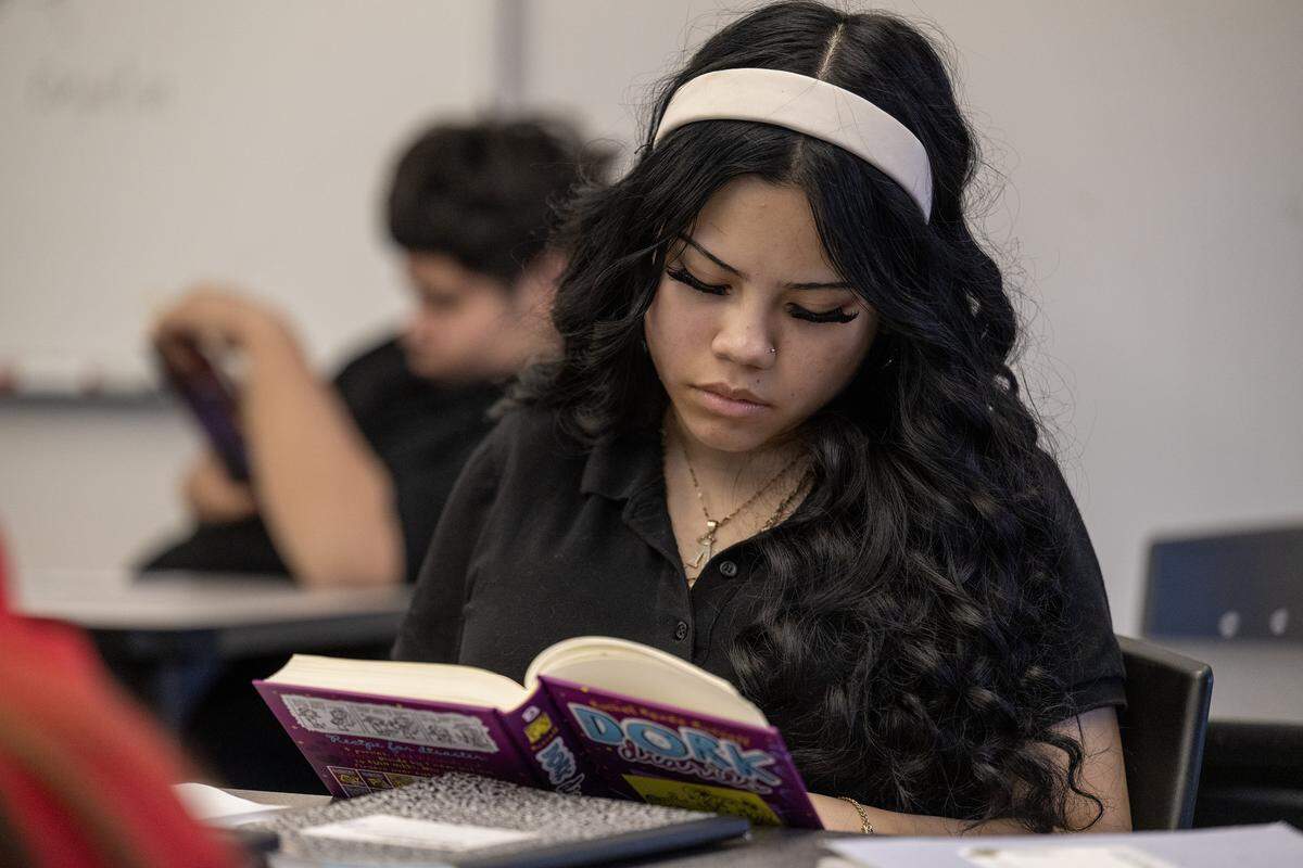 Nayeli, a seventh grade student, reads a classroom library book during class on Thursday, Dec. 4, 2025, at Guadalupe Centers Middle School, in Kansas City. The school does not have a library, so teacher Christopher Leavens, has started a small library in his classroom for the students to have access to more books.