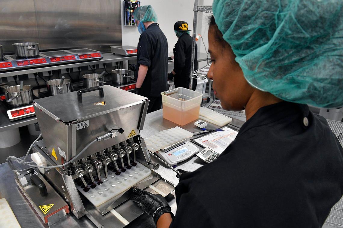 Shantel Lathrop uses a machine to dispense gummy liquid into molds during the manufacturing process at Clovr in Kansas City.