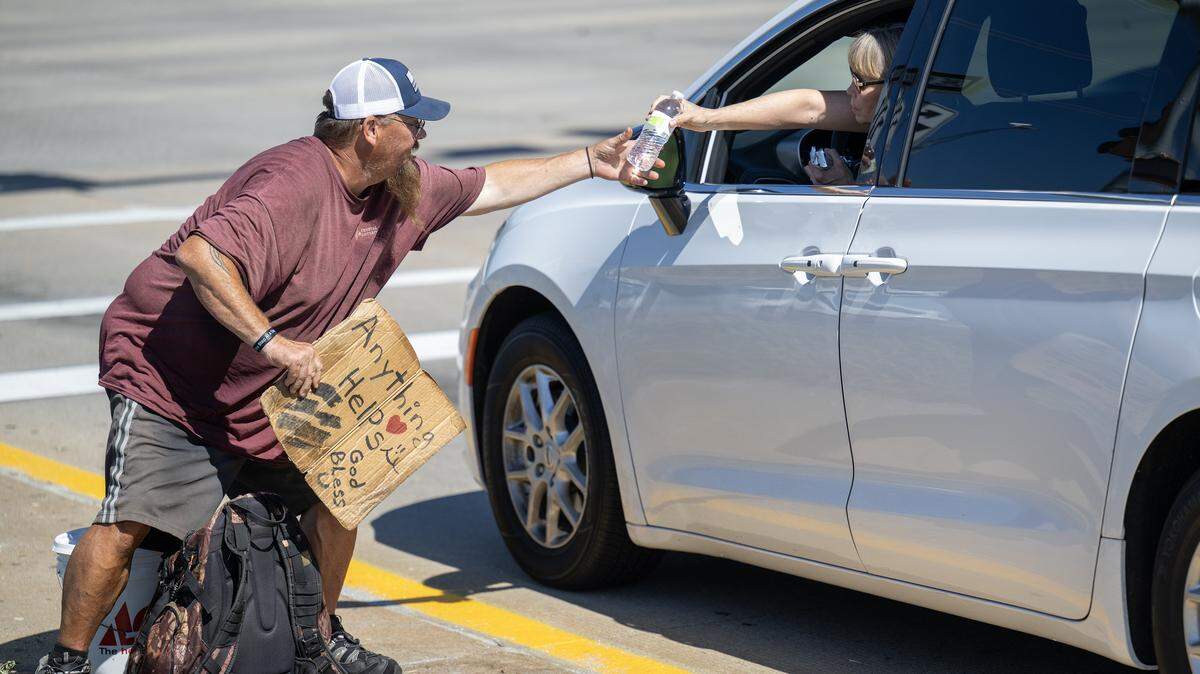 Dennis Richardson, 51, accepted a bottle of water from a driver while he was working the intersection of U.S. 69 and West 87th Street in Overland Park on Friday, September 26, 2025. Richardson said he has been experiencing homelessness since he was about 12 years old, when he ran away to escape an abusive situation. He plans to go to Project 1020, a cold weather shelter where he stayed for four months last year, when it opens on December 1st.