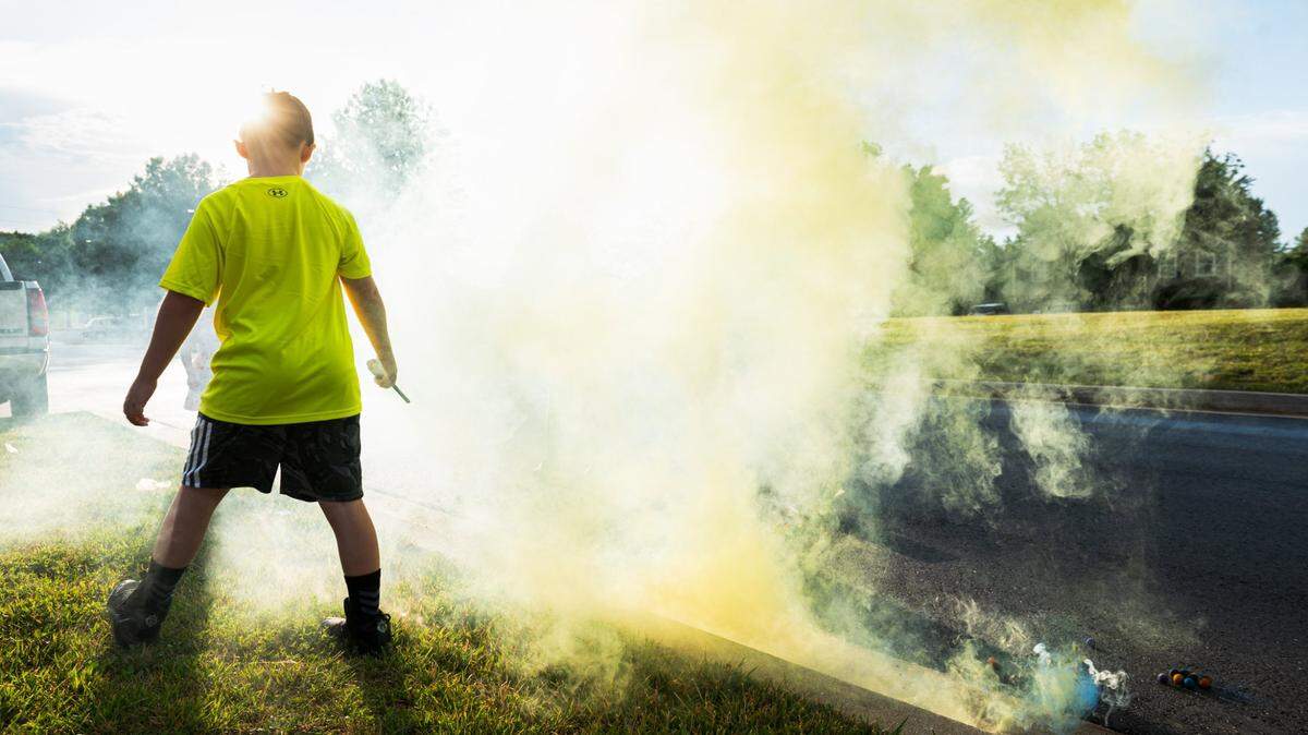 A child steps back after lighting a smoke bomb in Blue Springs in this file photo.