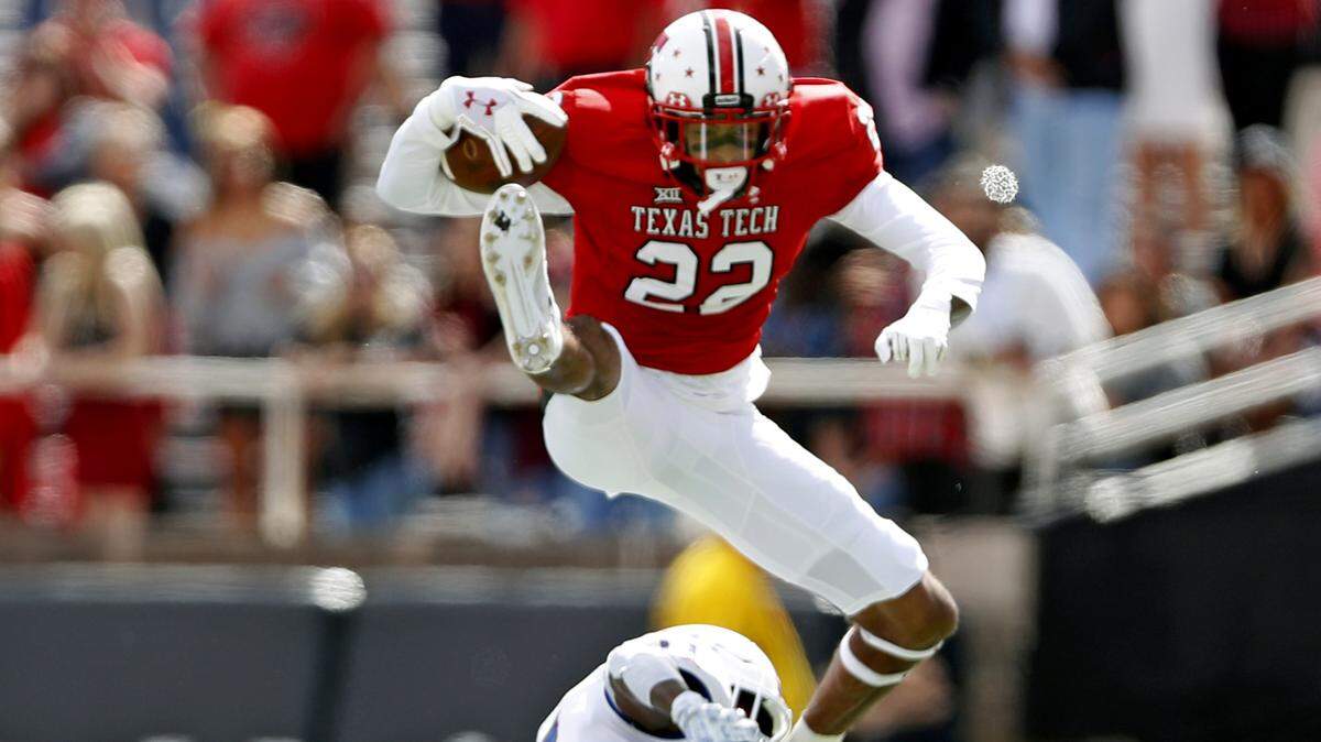 Texas Tech’s Seth Collins jumped over Kansas’ Mike Lee during the first half on Saturday in Lubbock, Texas.