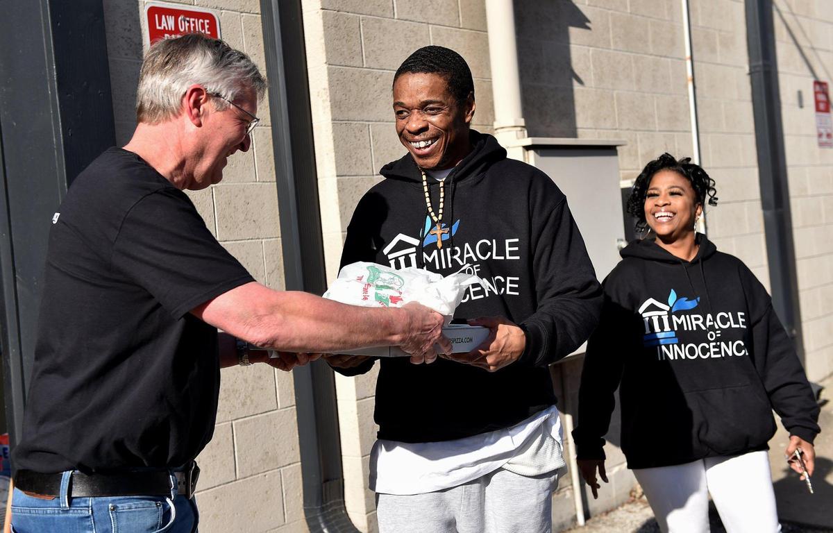 Miracle of Innocence volunteer Brain Dale, left, hands Keith Carnes a pizza, one of Carnes’ favorite foods, as Valerie Burton, also with Miracle of Innocence watches. Carnes was freed from prison Monday, April 11, 2022, after 18 years. The prosecutor’s office declined to file charges after the Missouri Supreme Court threw out his conviction for murder and armed criminal action.