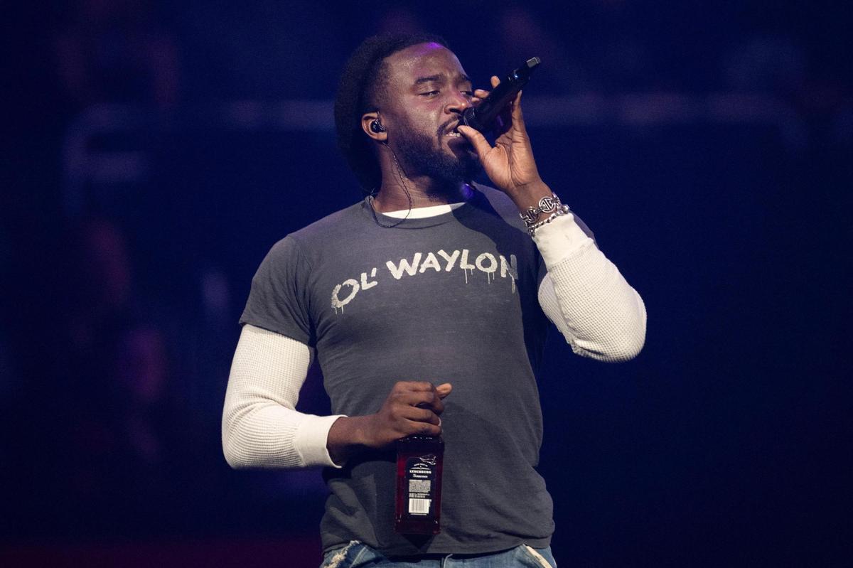 Shaboozey holds a bottle of Jack Daniel’s whiskey as he performs on stage during the Beautifully Broken Tour at T-Mobile Center.