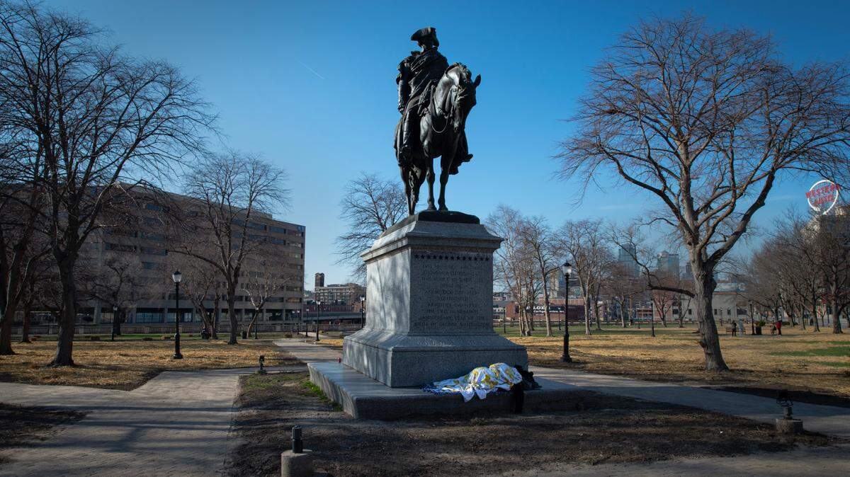 A houseless person bundled in blankets slept at the base of the George Washington statue Wednesday at the entrance of Washington Square Park in Kansas City. The park, a popular gathering spot for houseless people, is getting spruced up ahead of the NFL Draft taking place at nearby Union Station at the end of April.