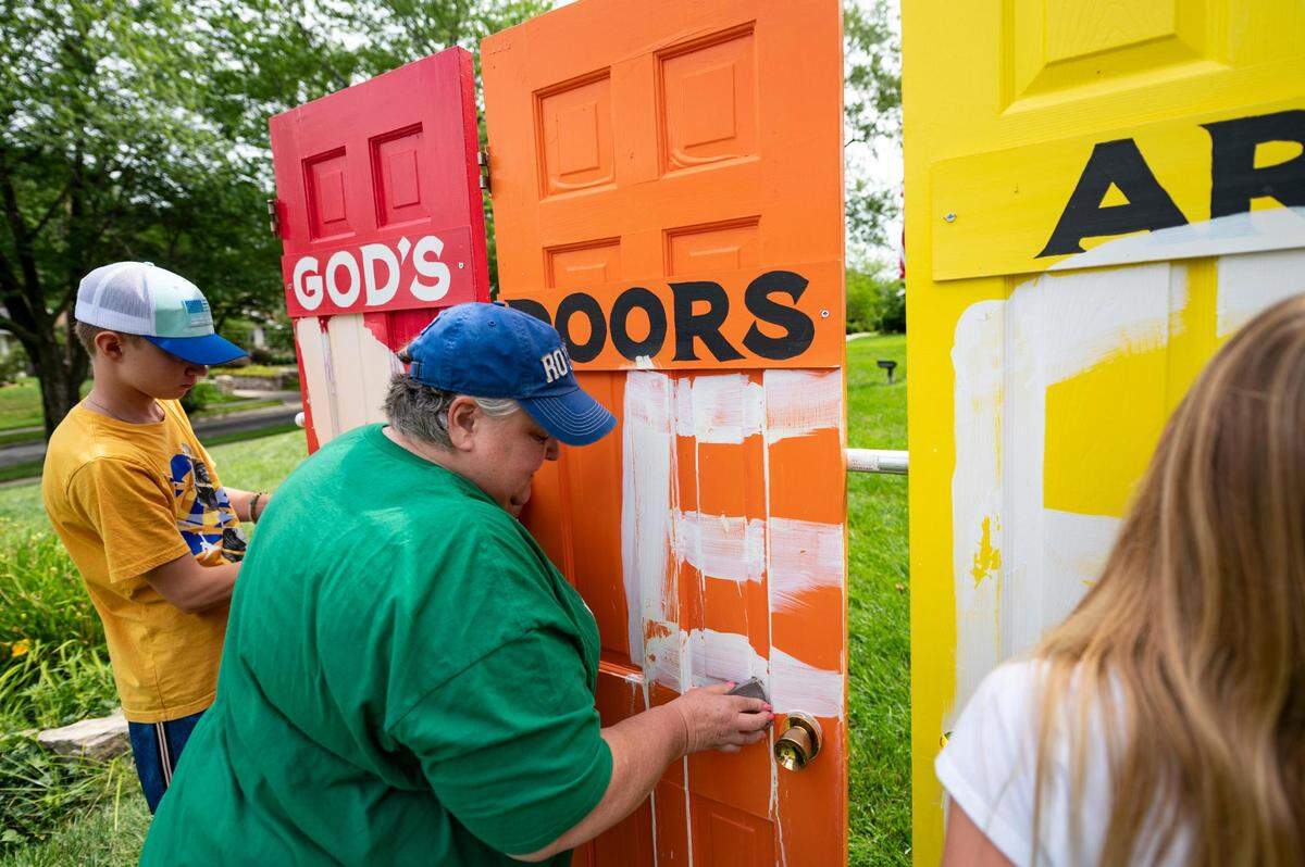 Catherine Kelly sands the anti-LGBTQ message from doors vandalized on the lawn of Kansas City United Church of Christ in Kansas City on July 7, 2022. Church and community members gathered quickly to remove the hateful message and repaint the symbolic doors.