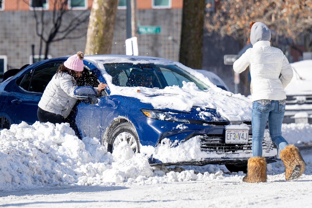 Residents assist a driver whose vehicle is unable to move from a parking spot due to snow, along Armour Boulevard on Monday, Jan. 6, 2025, in Kansas City.