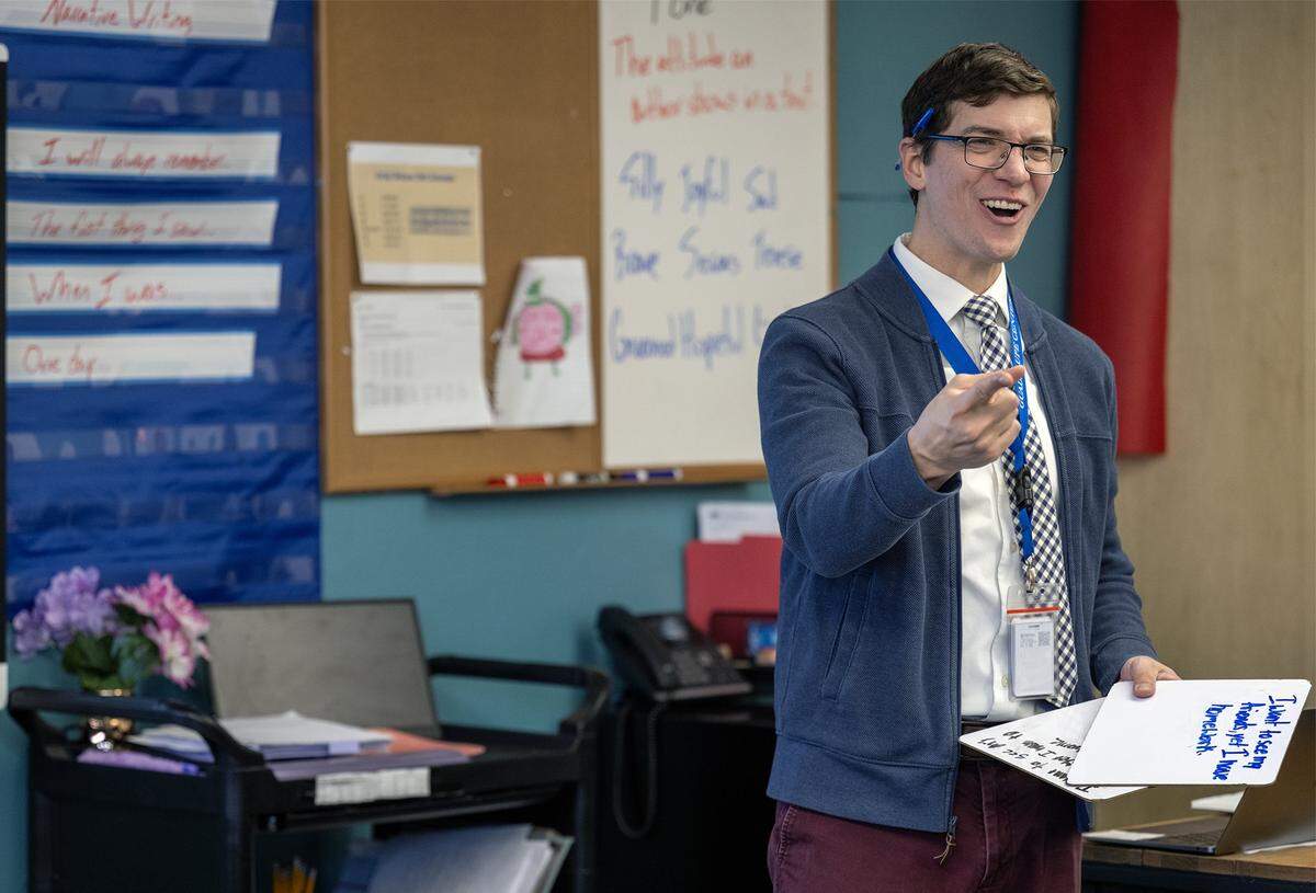 Christopher Leavens, an English language development teacher at Guadalupe Centers Middle School, laughs as he teaches a lesson on sentence structure to seventh grade students on Thursday, Dec. 4, 2025, in Kansas City. A good book, he says, can help change a student’s life.
