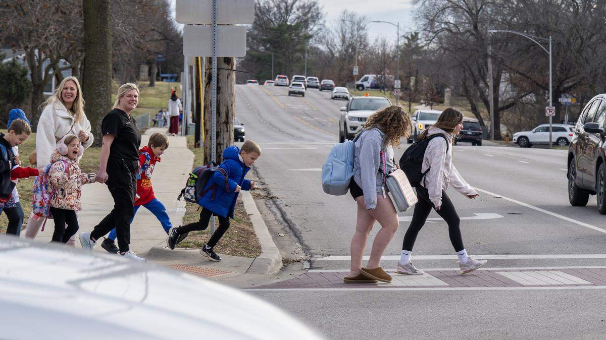 Adults and children walk across Mission Road near Corinth Elementary School on Thursday, Jan. 15, 2026.