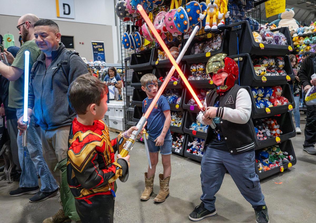 Maverick Villatoro, left, and his brother Nelson Villatoro play with lightsabers during Planet Comicon at the Kansas City Convention Center on Friday, March 21, 2025.