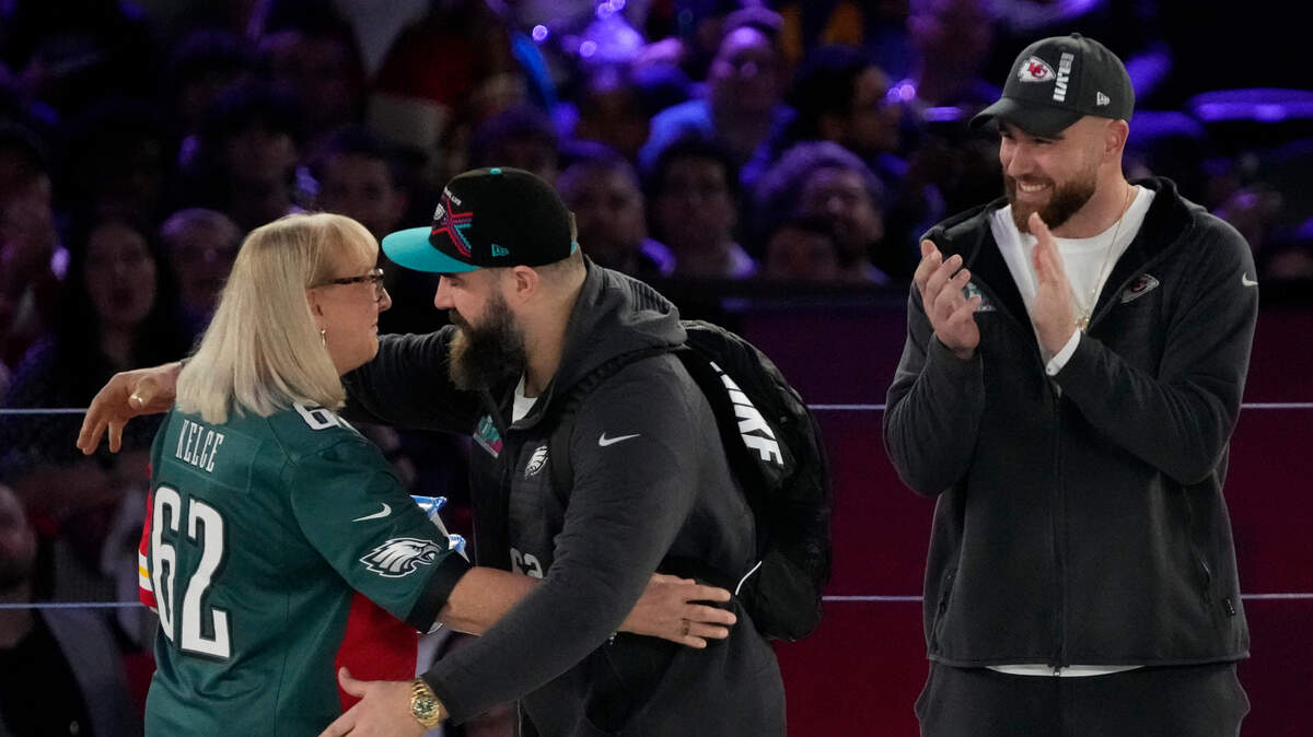 Donna Kelce hugs her son Philadelphia Eagles center Jason Kelce (62) while her other son Kansas City Chiefs tight end Travis Kelce (87) claps during Super Bowl Opening Night at Footprint Center.