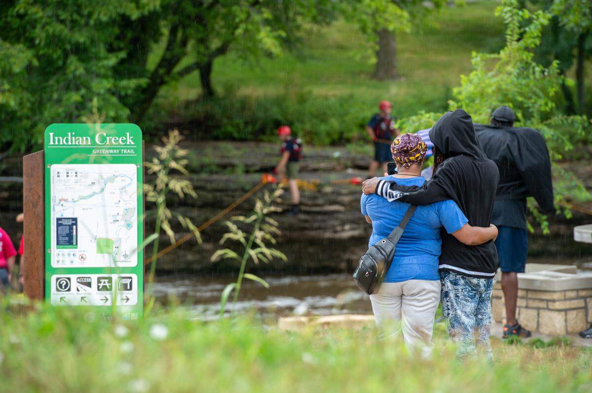 The family of Trevion Mcafee look on as KCFD firefighters continue to search for the 19-year-old at Indian Creek Monday morning. Mcafee, a sophomore at Metropolitan Community College, was possibly swept away by currents at Indian Creek Sunday night.