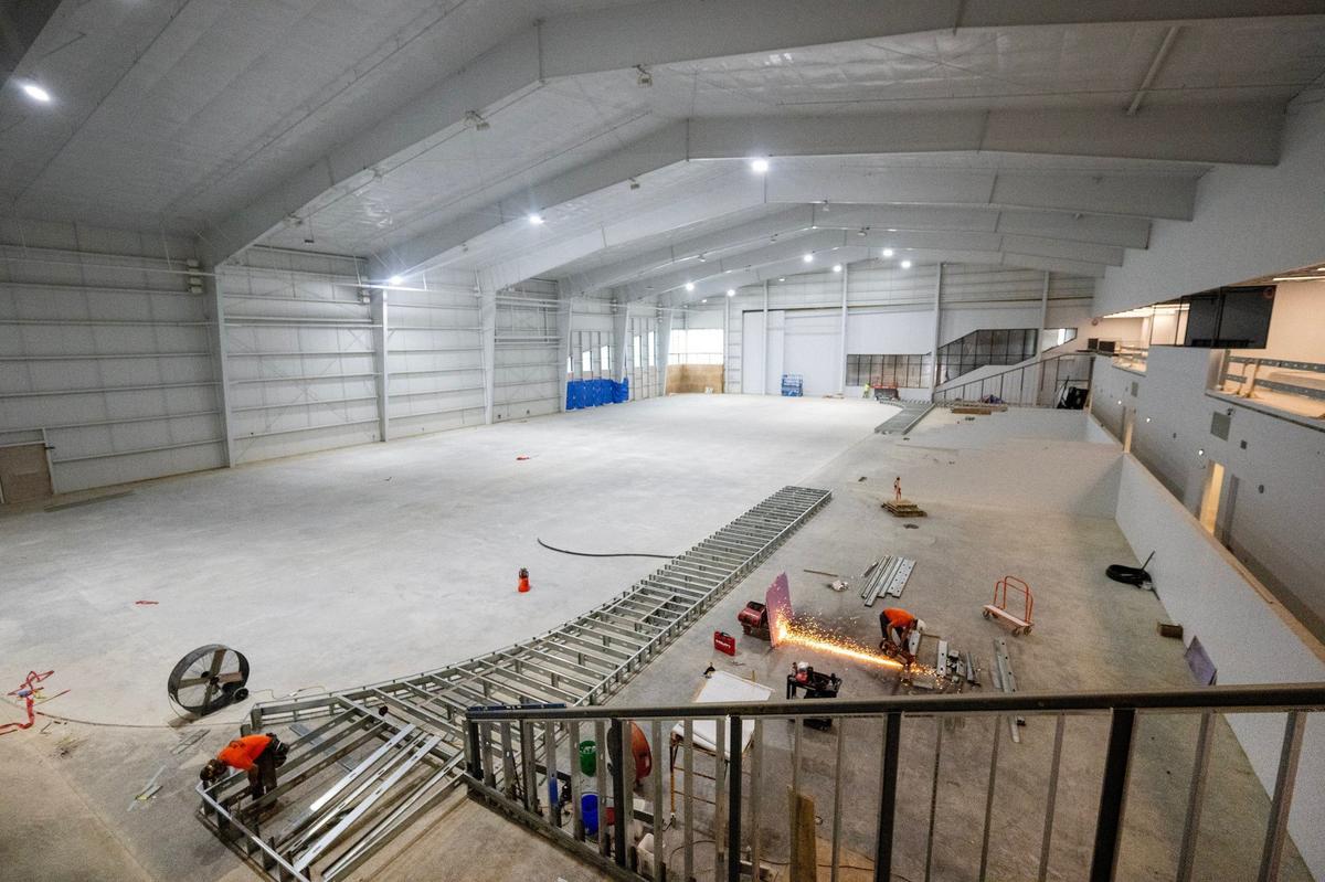 Zach McClure, left, and Noel Terrazus of Metro Interiors of Lee’s Summit work on the frame work which will house the seating at the hockey arena under construction at the AdventHealth Sports Park at Bluhawk in Overland Park.