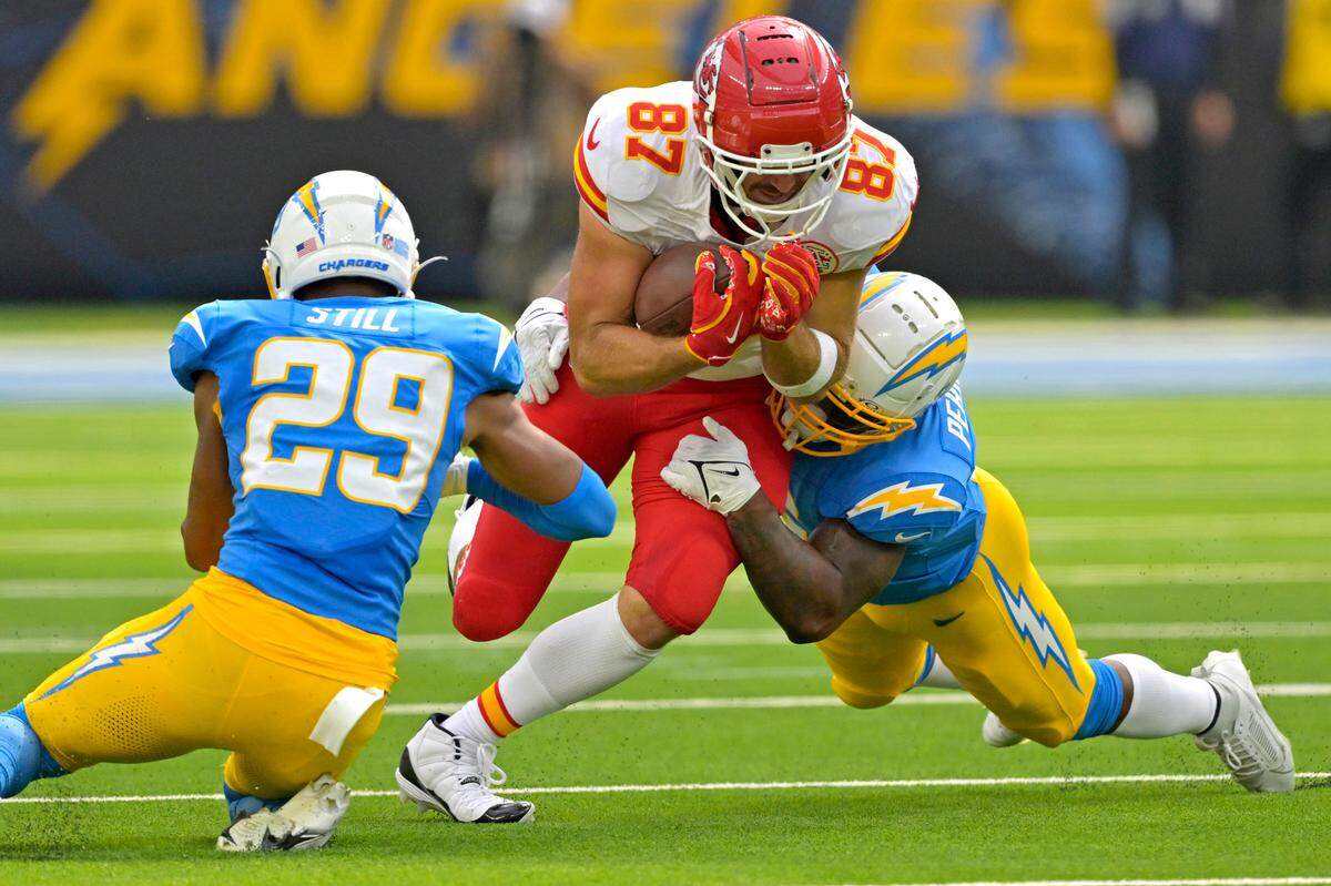 Kansas City Chiefs tight end Travis Kelce (87) is stopped by Los Angeles Chargers defensive tackle CJ Okoye (69) an cornerback Tarheeb Still (29) after a complete pass in the first half at SoFi Stadium.