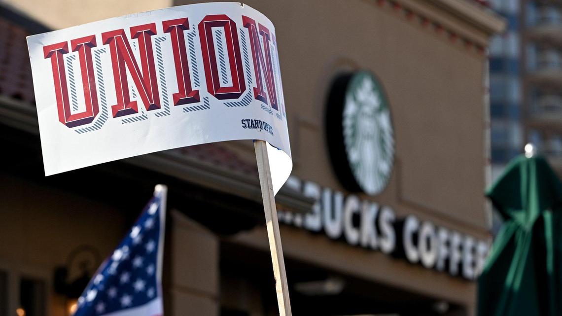 A protester waves a sign that read “unionize” near the Country Club Plaza Starbucks store where dozens of Starbucks employees and union supporters protested alleged anti-union tactics by the company Thursday, March 3, 2022.