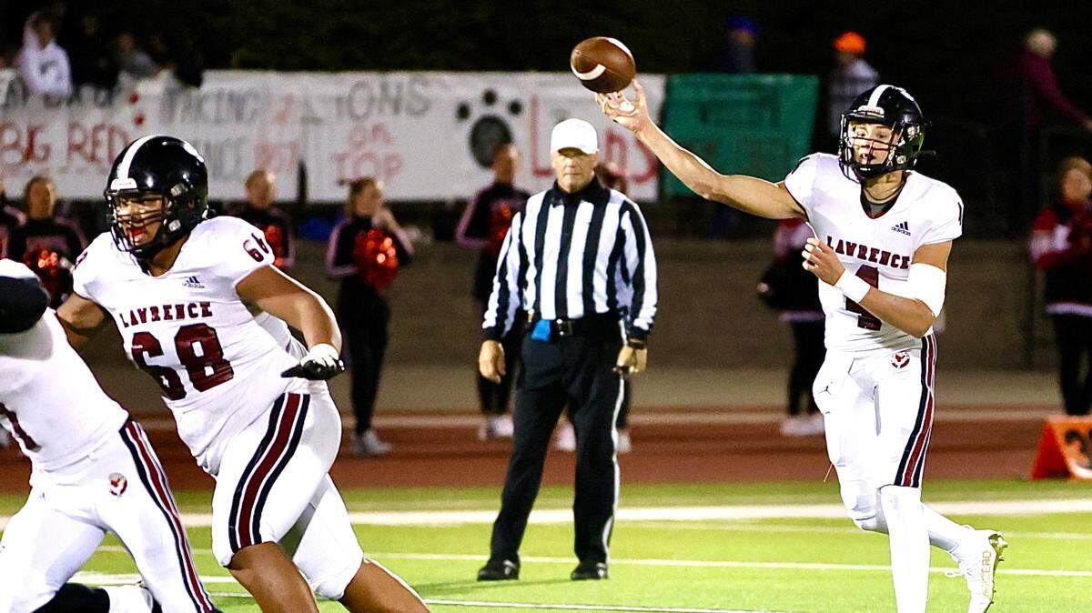 Lawrence’s Banks Bowen slings a pass while Bailey Johnson blocks on Friday night.