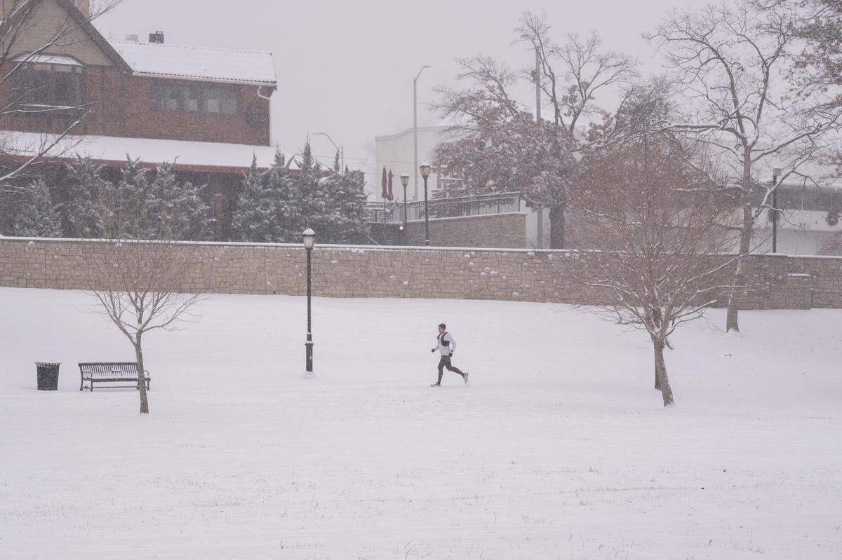 A man runs in the snow at Mill Street Park as snow blanketed the Kansas City metro area on Monday.