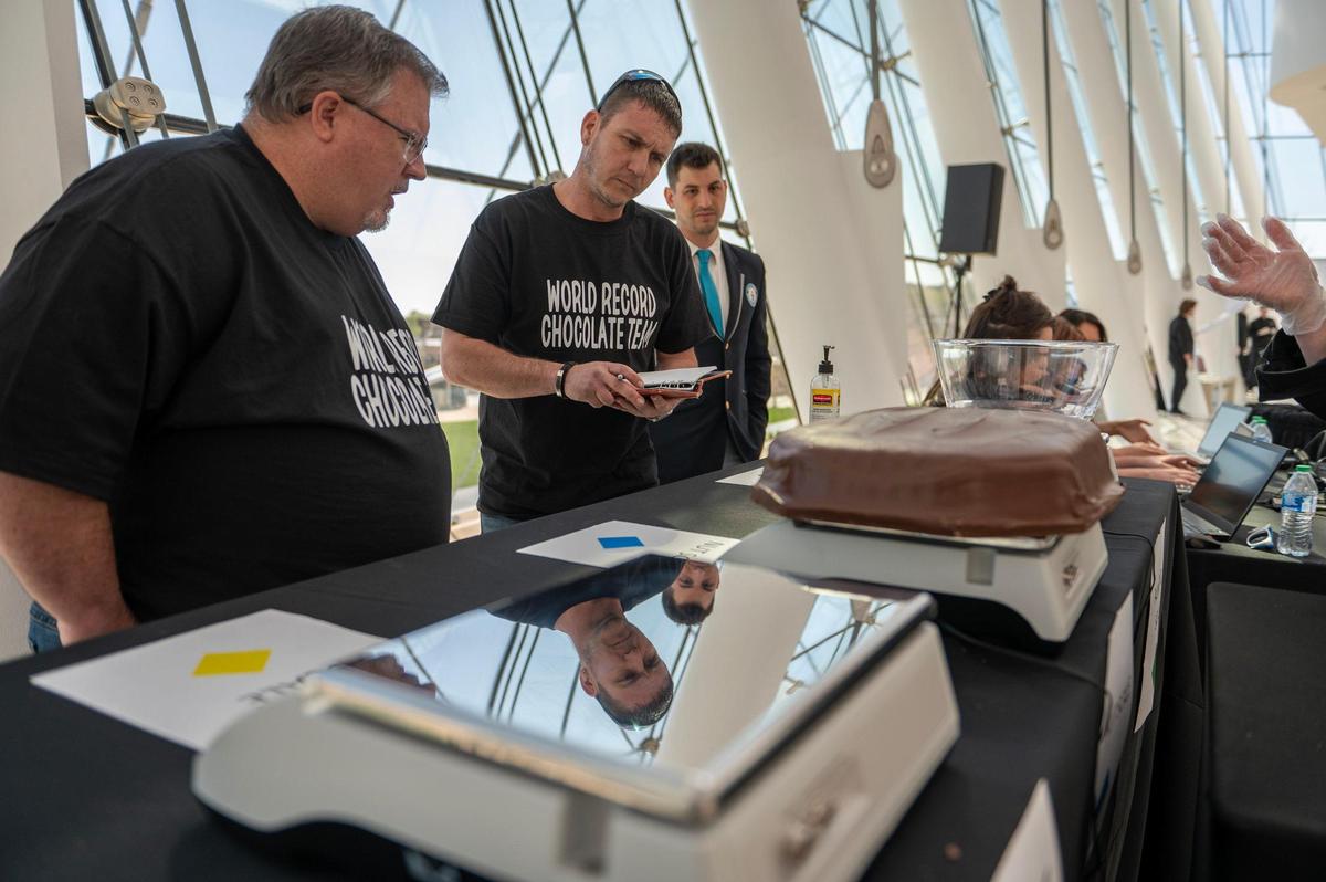 Russ Bishop, center, member of Russell Stover’s world record chocolate team, weighs in giant slabs of chocolate during Monday’s attempt to break the Guinness World Record for the largest box of chocolate.