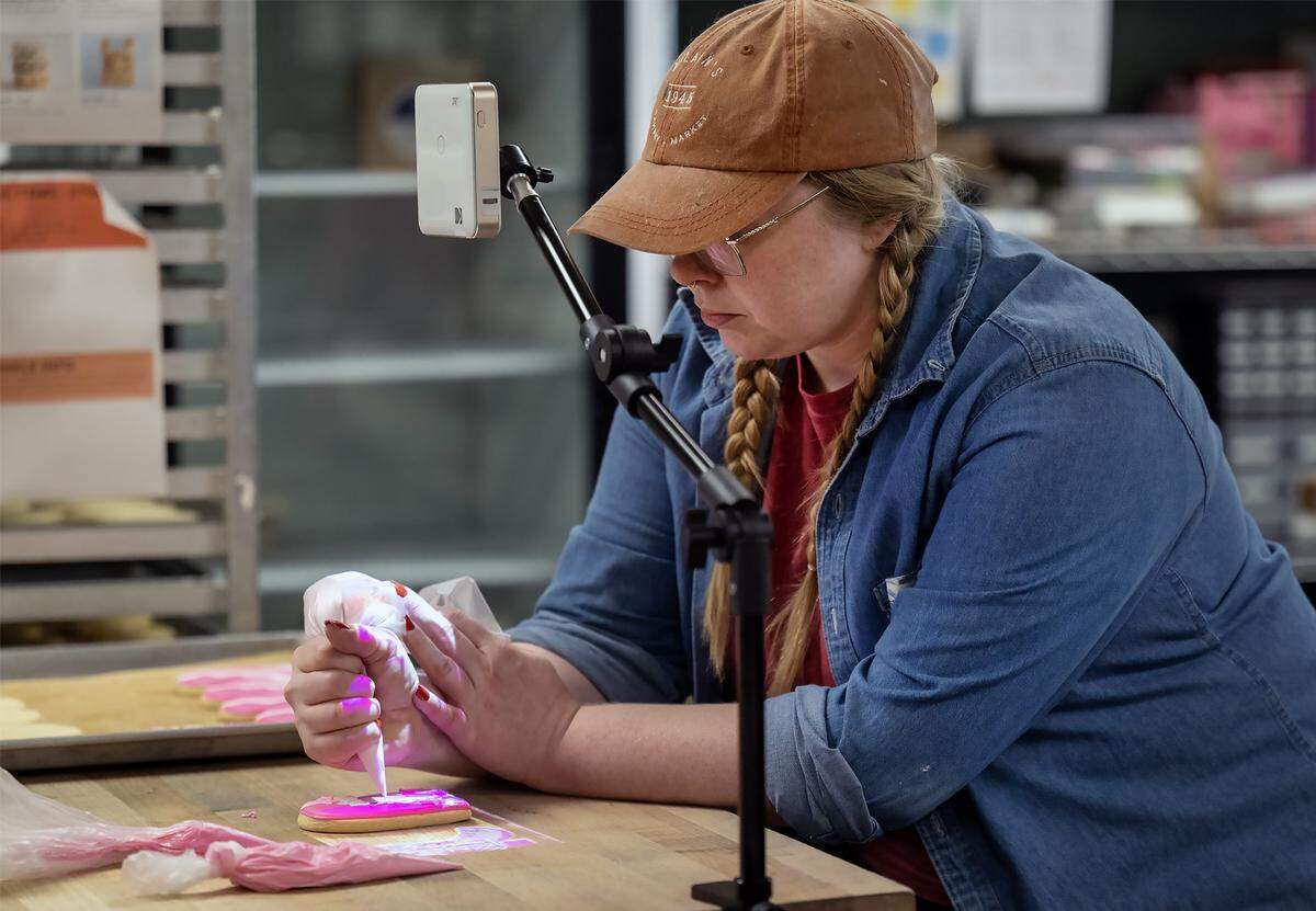 Olivia Lynn project a design onto a Chappell Roan-themed sugar cookie which decorates in icing on Thursday, Oct. 2, 2025, at McLain's Bakery in Waldo. Local bakeries are seeing a significant demand for cookies to celebrate pop stars Taylor Swift and Chappell Roan.