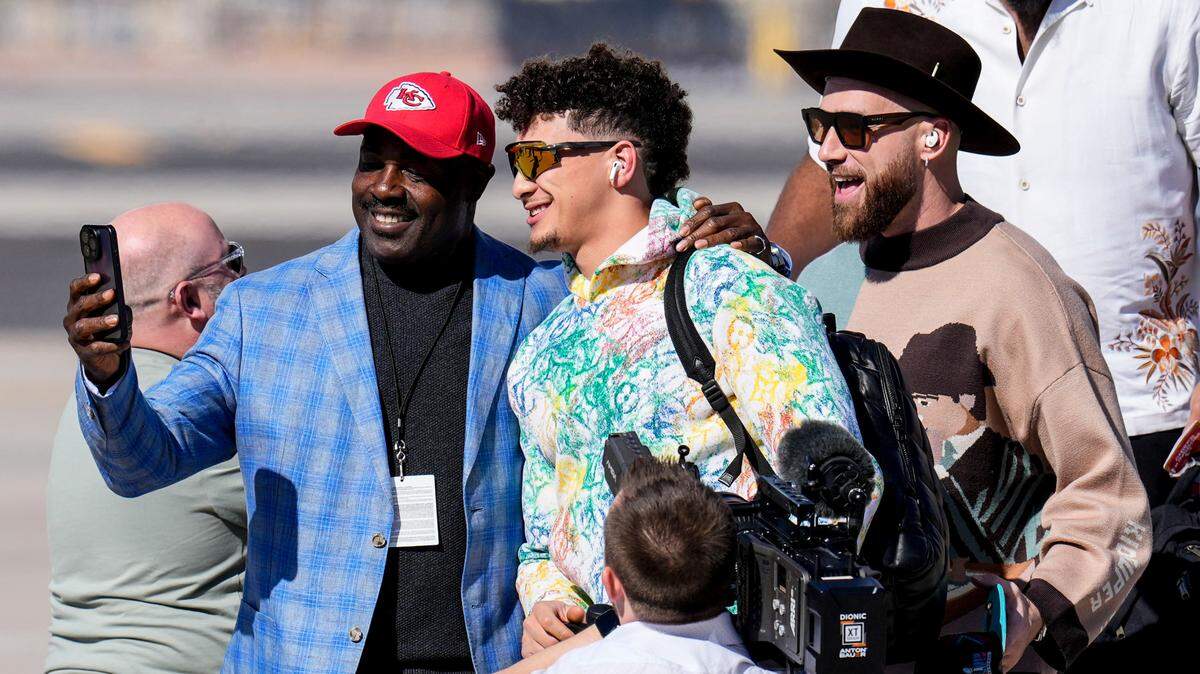 Former Chief player Christian Okoye, left, takes a photo with Kansas City Chiefs quarterback Patrick Mahomes and tight end Travis Kelce as they arrive ahead of Super Bowl 57, Sunday, Feb. 5, 2023, in Phoenix. The Kansas City Chiefs will play the Philadelphia Eagles on Sunday.