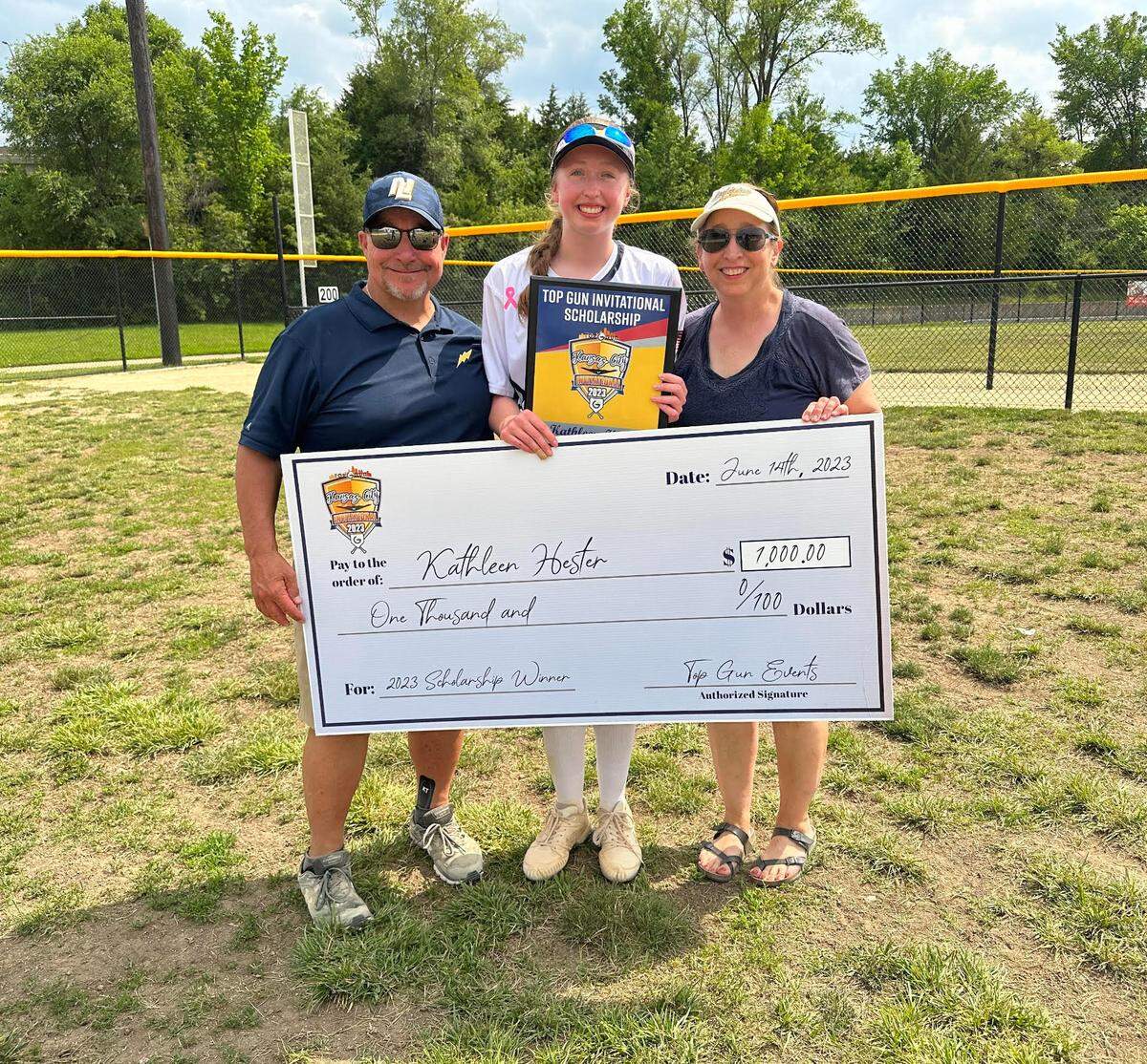 Scholarship winner Kathleen Hester of New Lenox Lighting 18u receives a Top Gun Invitational scholarship check with coach Jim Abbott (left) and mother Lori Hester (right).