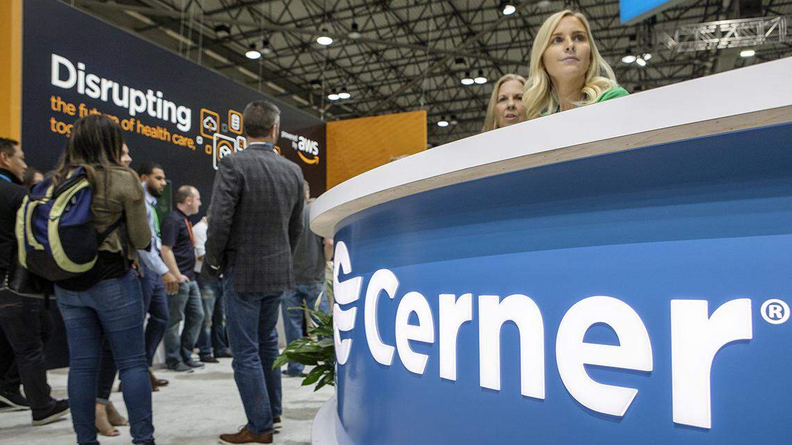 Cerner employees sit at a help desk at the Cerner Health Conference Tuesday, Oct. 8, 2019, at the Municipal Auditorium in the Kansas City Convention Center. Behind them is a stand for Amazon Web Services, which provides cloud service for Cerner.